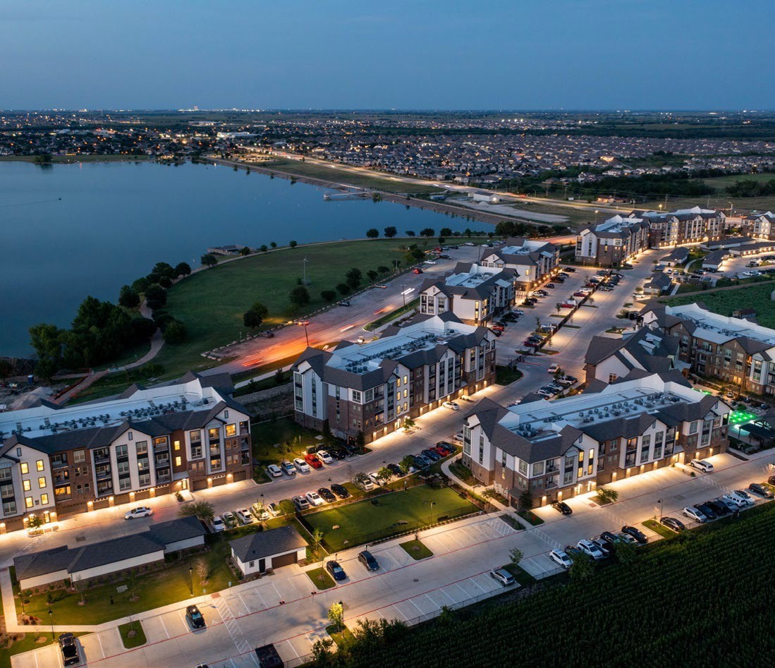 Aerial view at dusk of a newly built Class A apartment community beside a lake