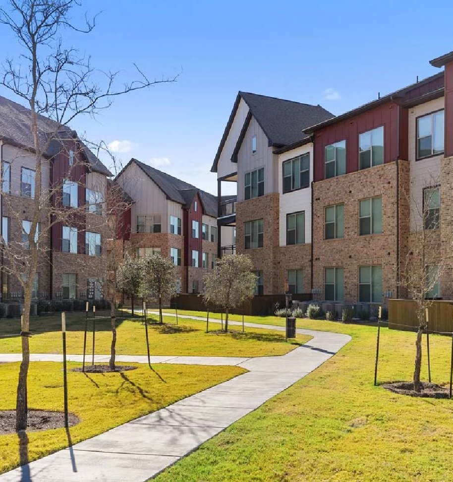 Newly built three-story garden apartment buildings around a landscaped lawn